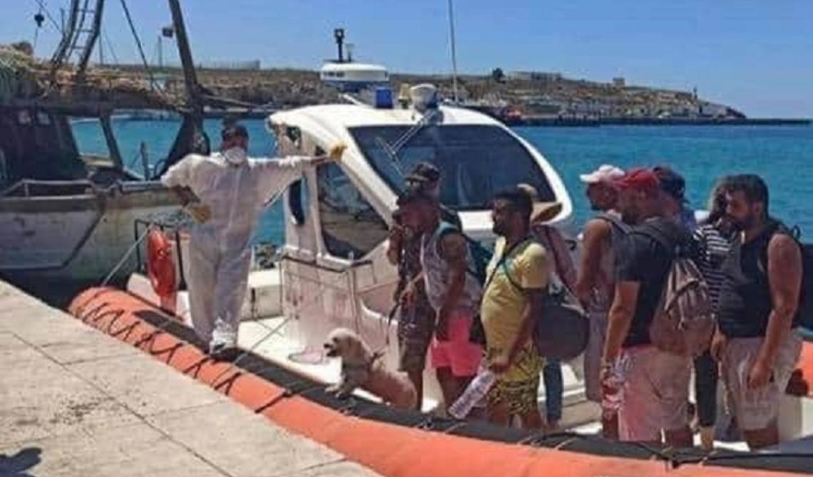 Lampedusa: lo sbarco di undici tunisini dal gommone dalla Guardia Costiera con bagagli, un barboncino al guinzaglio e cappelli di paglia
