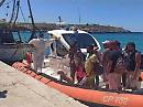 Lampedusa: lo sbarco di undici tunisini dal gommone della Guardia Costiera con bagagli, un barboncino al guinzaglio e cappelli di paglia